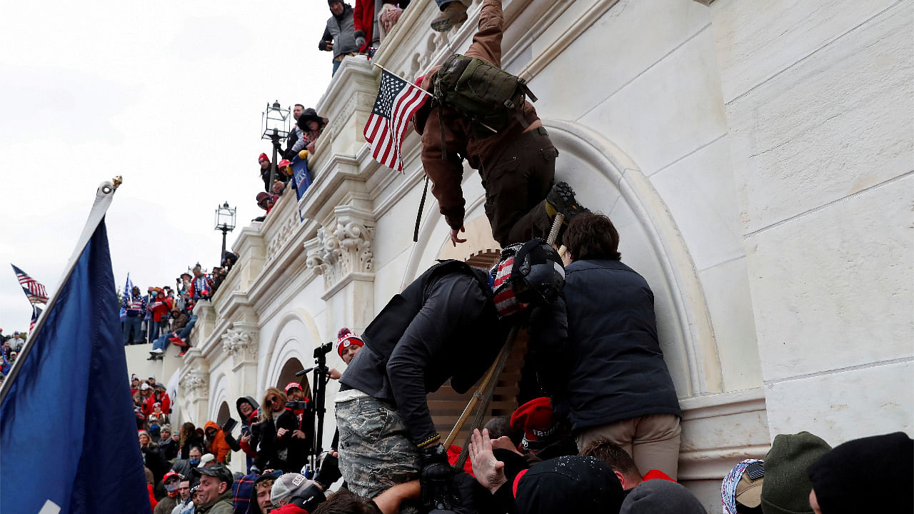 Pro-Trump protesters scale a wall as they clash with police during a rally to contest the certification of the 2020 U.S. presidential election results. Credit: Reuters Photo