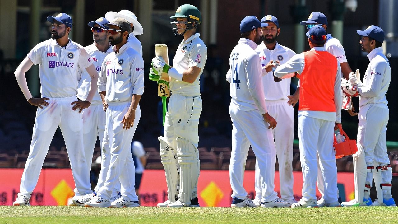 Indian players along with Australia's captain Tim Paine (C) stand as the game was stopped after allegedly some remarks were made by the spectators on the fourth day of the third cricket Test match between Australia and India at the Sydney Cricket Ground (SCG) in Sydney on January 10, 2021. Credit: AFP Photo