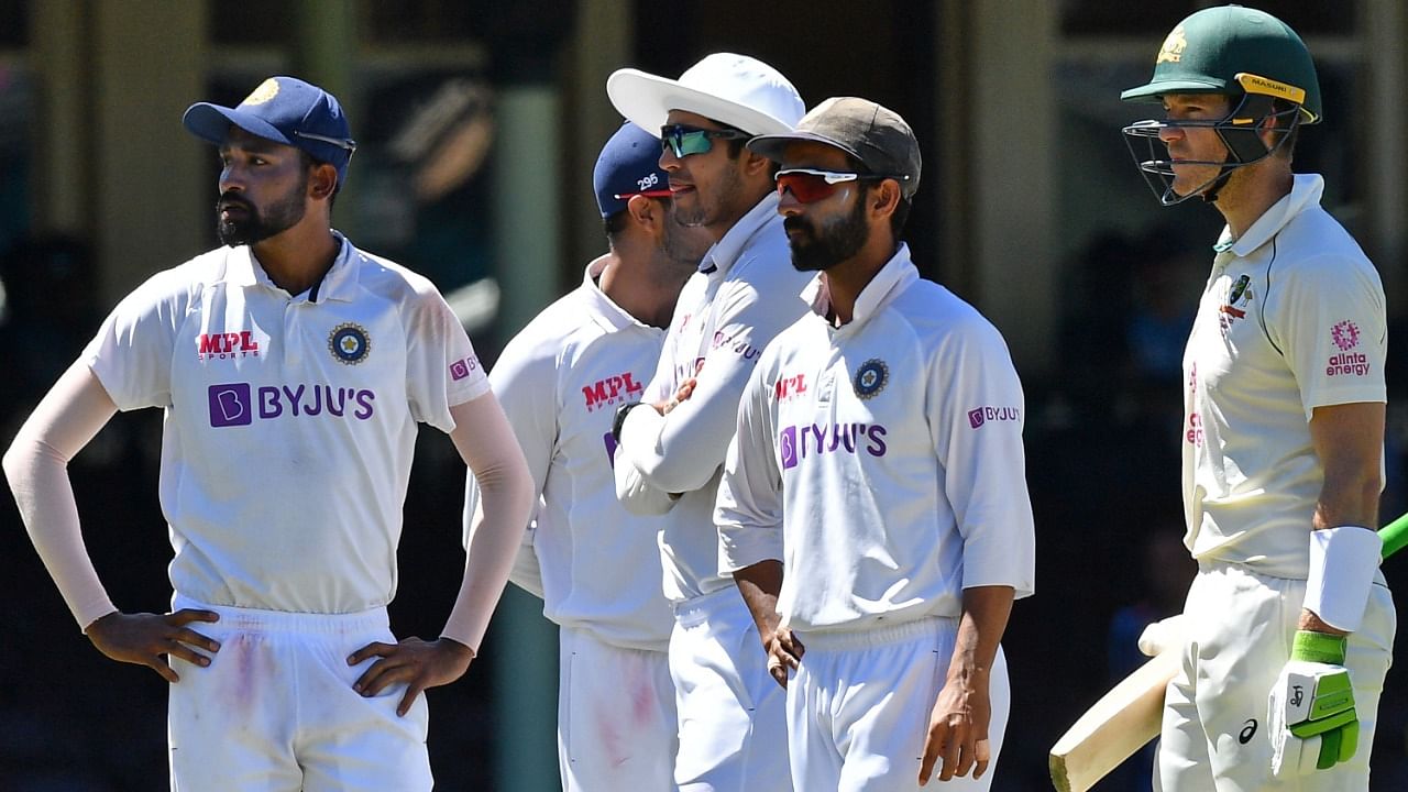 Indian players along with Australia's captain Tim Paine (R) stand as the game was halted after allegedly some remarks were made by the spectators on the fourth day of the third cricket Test match between Australia and India at the Sydney Cricket Ground (SCG) in Sydney on January 10, 2021. Credit: AFP Photo