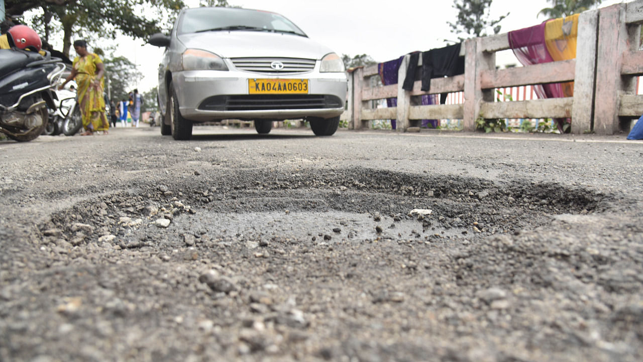 Vehicles running on potholes at Danvantri road in Bengaluru. Credit: DH Photo/Janardhan B K