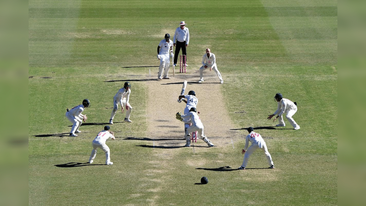 India's Hanuma Vihari (C) plays a shot as Australia's Nathan Lyon (top R) watches during the fifth day of the third cricket Test match between Australia and India at the Sydney Cricket Ground (SCG) in Sydney on January 11, 2021. Credit: AFP Photo