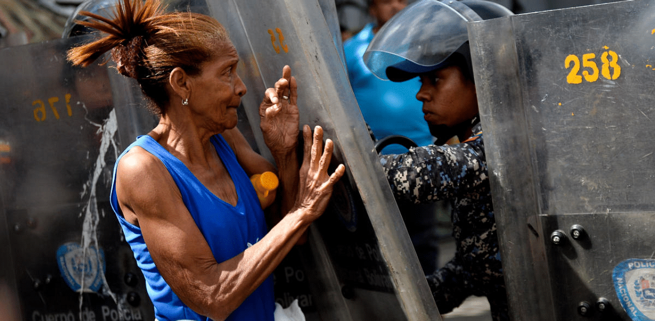  A woman confronts riot police during a protest against the shortage of food, amid Fuerzas Armadas avenue in Caracas. Credit: AFP Photo