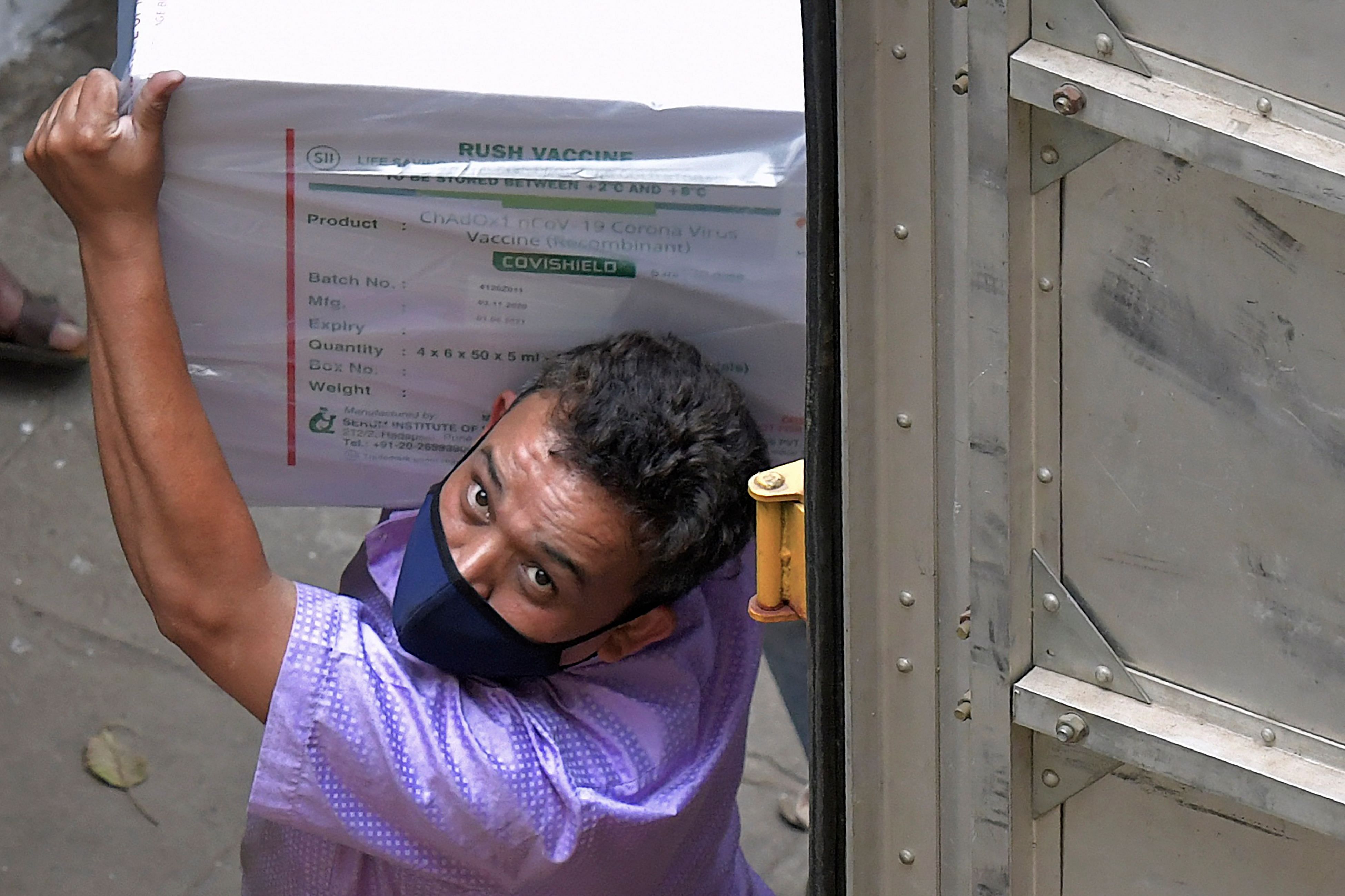 Workers transfer carton boxes of a Covishield vaccine developed by Pune based Serum Institute of India (SII) that arrived in a truck into the Karnataka Health Department cold storage facility in Bangalore on January 12, 2021, in preparation for the first round of vaccination drive scheduled to begin across the country from January 16. Credit: AFP Photo