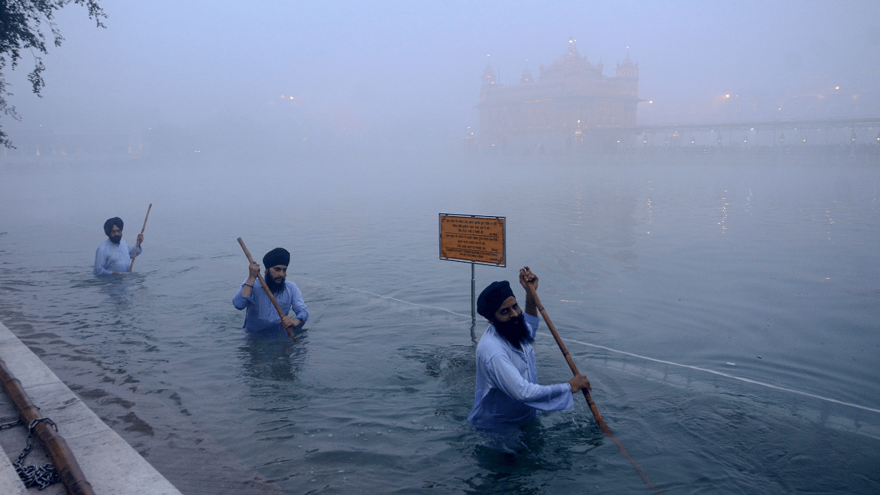 'Sewadars' (volunteers) clean the holy pond at Harmandir Sahib, or Golden Temple, on a cold foggy morning, in Amritsar. Credit: PTI File Photo