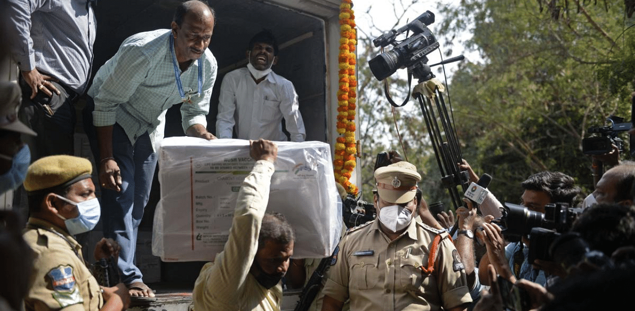 Policemen stand guard as an official unloads a box containing Covishield vaccine at the Commissionerate of Health and Family Welfare in Hyderabad. Credit: AFP Photo