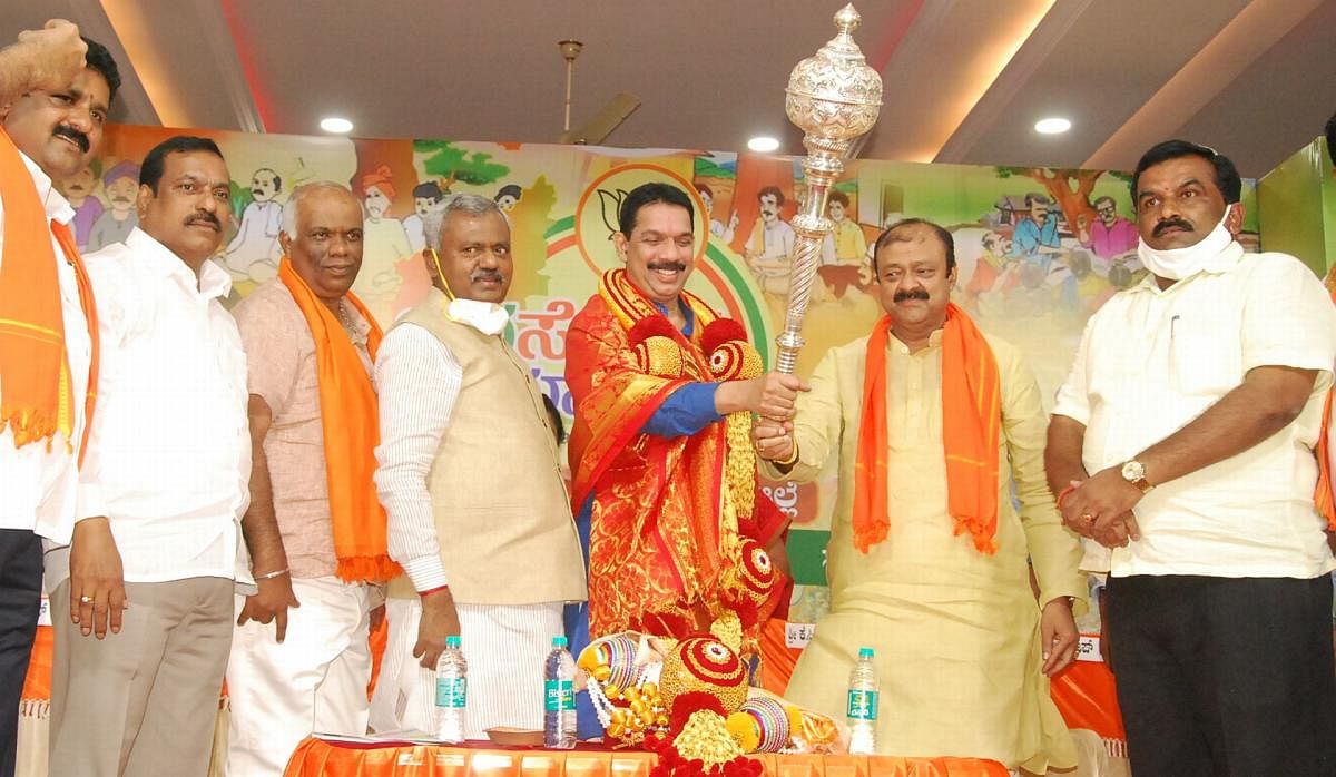 Minister for Municipal Administration, Horticulture and Sericulture K C Narayana Gowda presents a mace to BJP state president Nalin Kumar Kateel in Mandya on Tuesday. Minister S T Somashekar and BJP leaders are seen. DH PHOTO