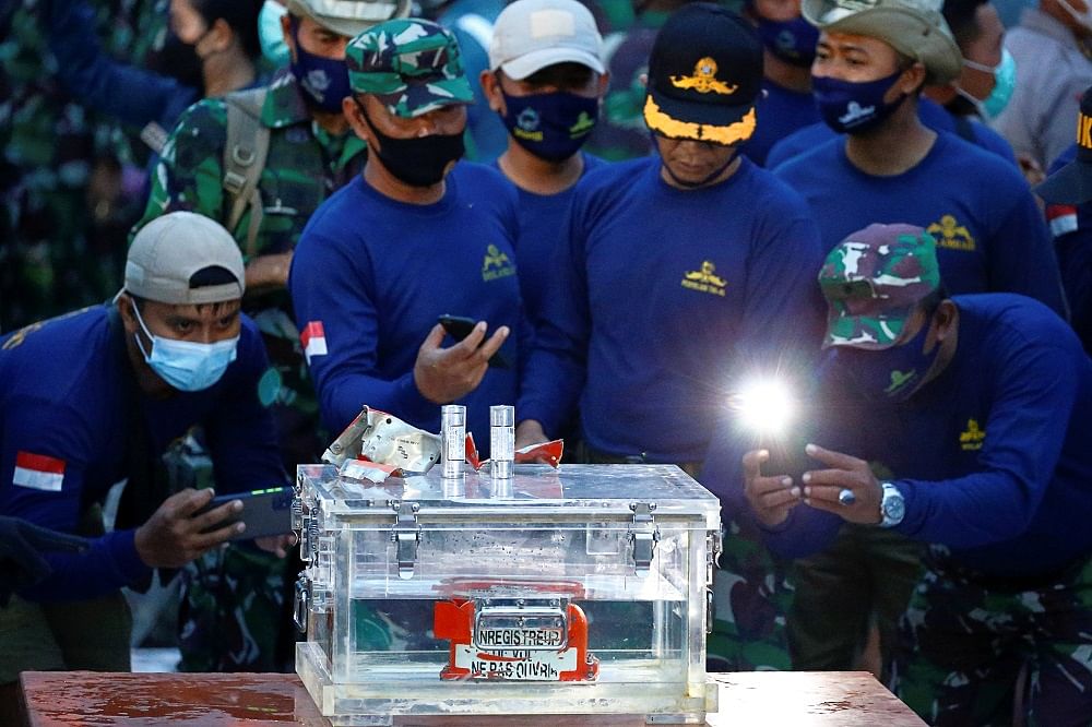 Indonesian Navy members take pictures of a part of the retrieved black box of Sriwijaya Air flight SJ 182, which crashed into the sea off the Jakarta coast. Credit: Reuters Photo