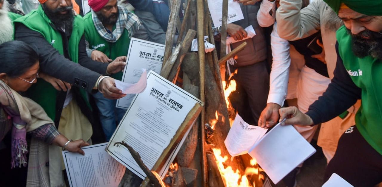 Farmer leaders burn copies of the new farm laws as they celebrate Lohri festival during their ongoing protest against the central government ,at Singhu border in New Delhi, Wednesday, Jan. 13, 2021. Credit: PTI Photo