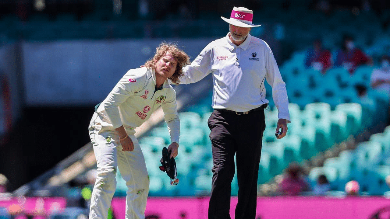 Australia's Will Pucovski (L) reacts after being hurt while fielding as umpire Paul Wilson watches during the fifth day of the third cricket Test match between Australia and India at the Sydney Cricket Ground (SCG) in Sydney. Credit: AFP Photo