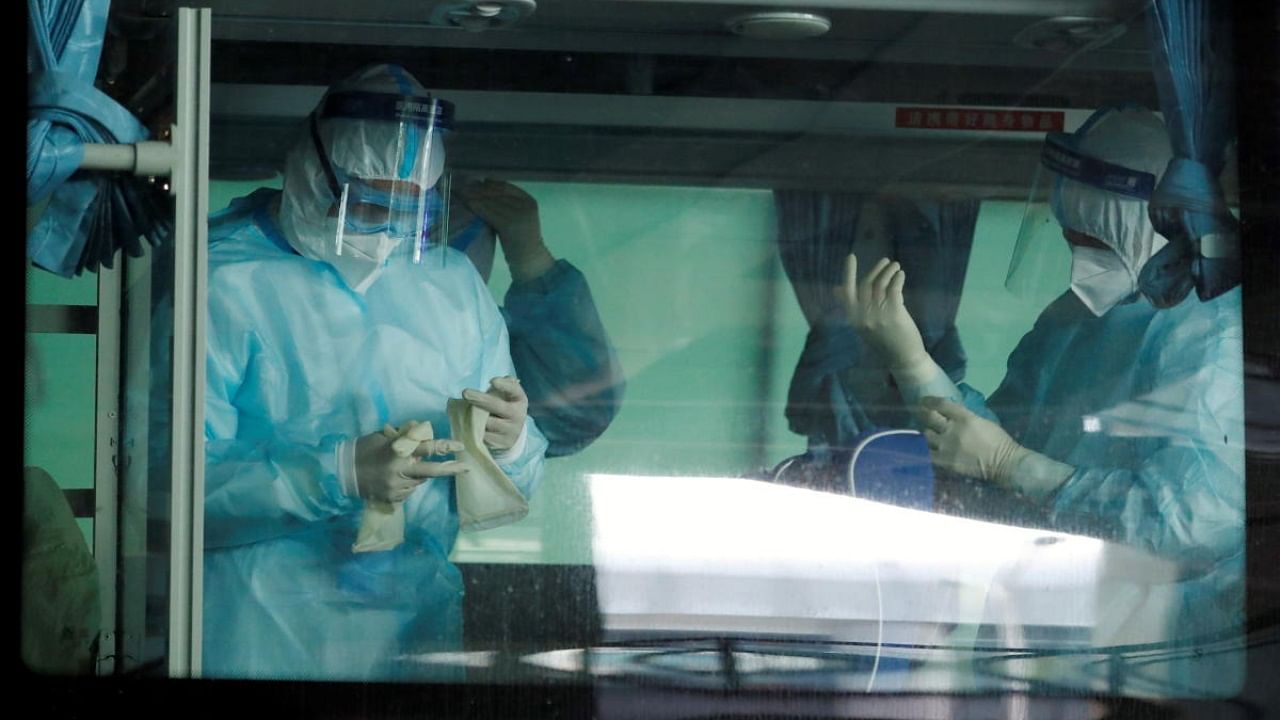 Medical workers get ready inside a bus before the expected arrival of a World Health Organisation (WHO) team in Wuhan. Credit: AFP Photo