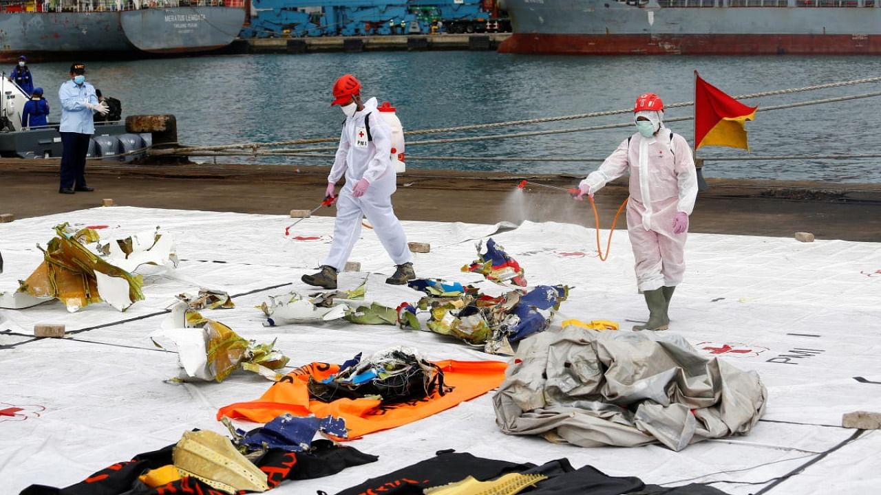 Members of Indonesia Red Cross spray disinfectant on suspected remains from Sriwijaya Air plane flight SJ 182 which crashed into the sea off the Jakarta coast, at Jakarta International Container Terminal port, Indonesia on January 11, 2021. Credit: Reuters Photo/Ajeng Dinar Ulfiana