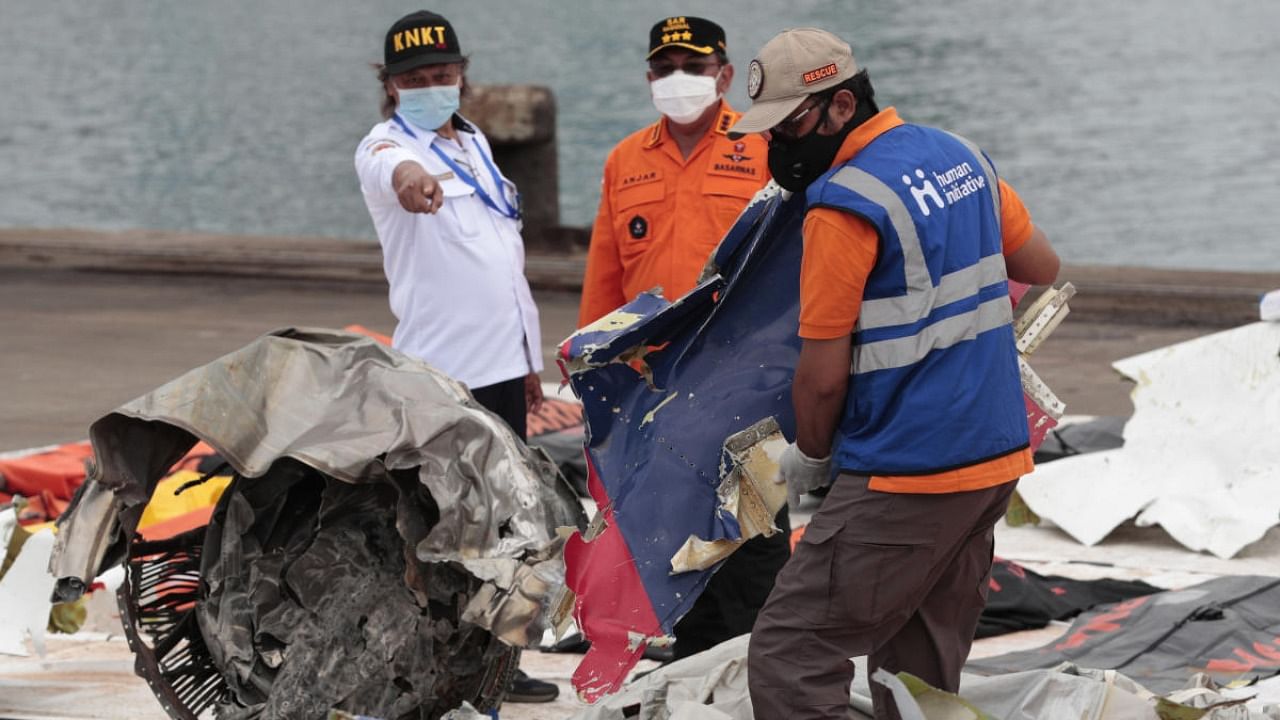 A worker carries parts of aircraft and debris retrieved from from the Java Sea where a Sriwijaya Air jet crashed at Tanjung Priok Port in Jakarta, Indonesia. Credit: AP/PTI Photo