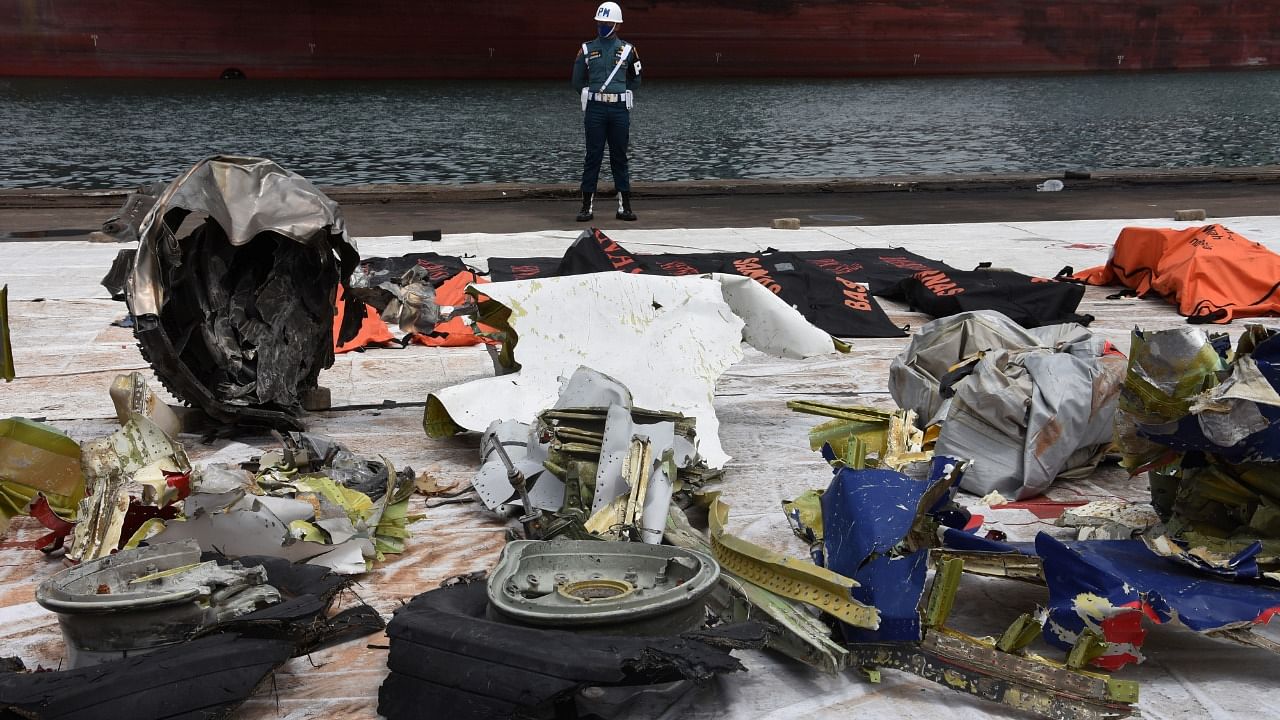 A member of the Indonesian navy personnel stands guard as the debris of Sriwijaya Air flight SJ 182, which crashed into the Java sea last week, are seen during a search and rescue operation at Tanjung Priok port in Jakarta. Credit: Reuters Photo