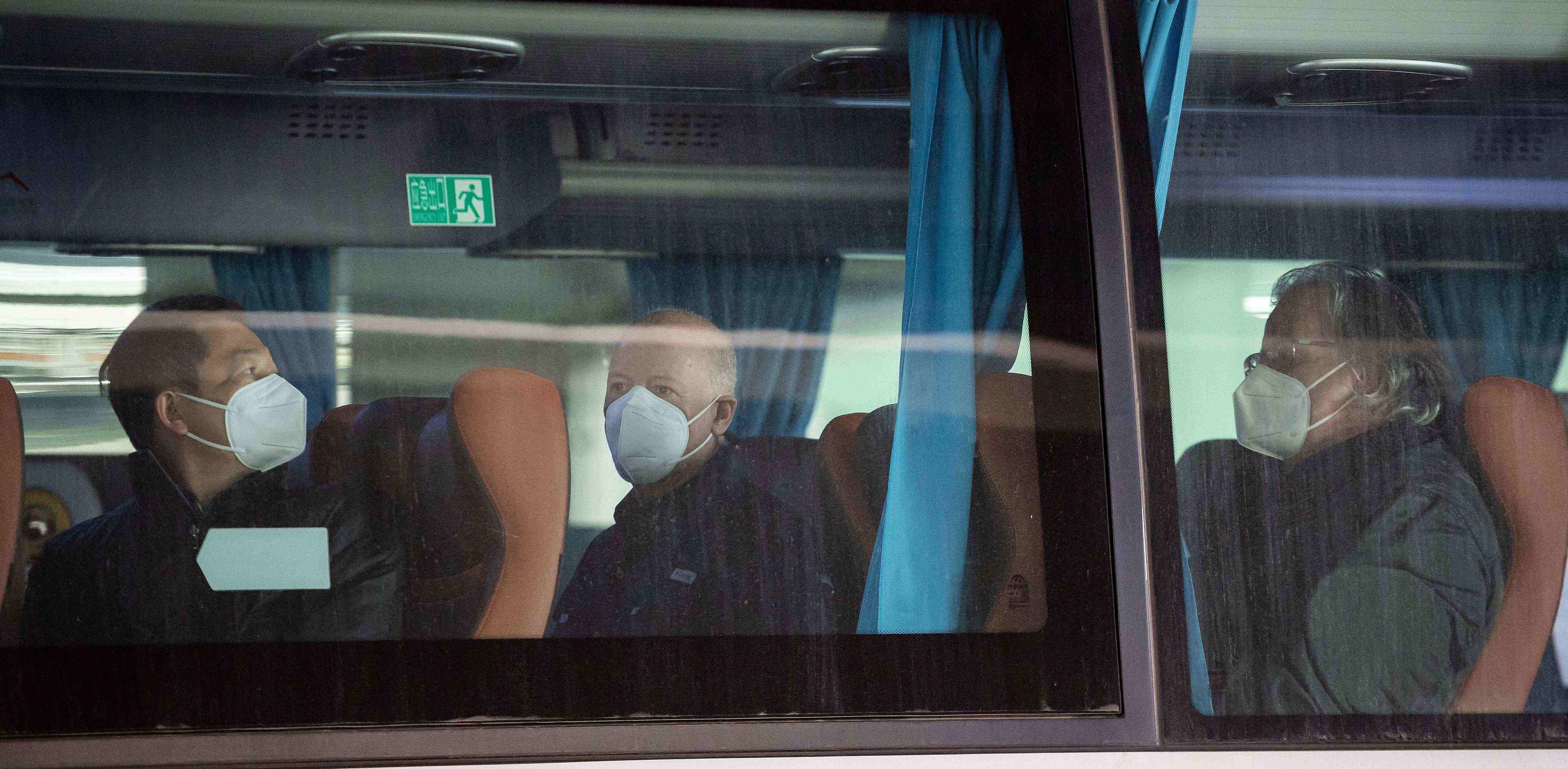 Members of the World Health Organization (WHO) team, including Peter Daszak (C) and Hung Nguyen (L), investigating the origins of the Covid-19 pandemic, board a bus following their arrival at a cordoned-off section in the international arrivals area at the airport in Wuhan. Credit: AFP