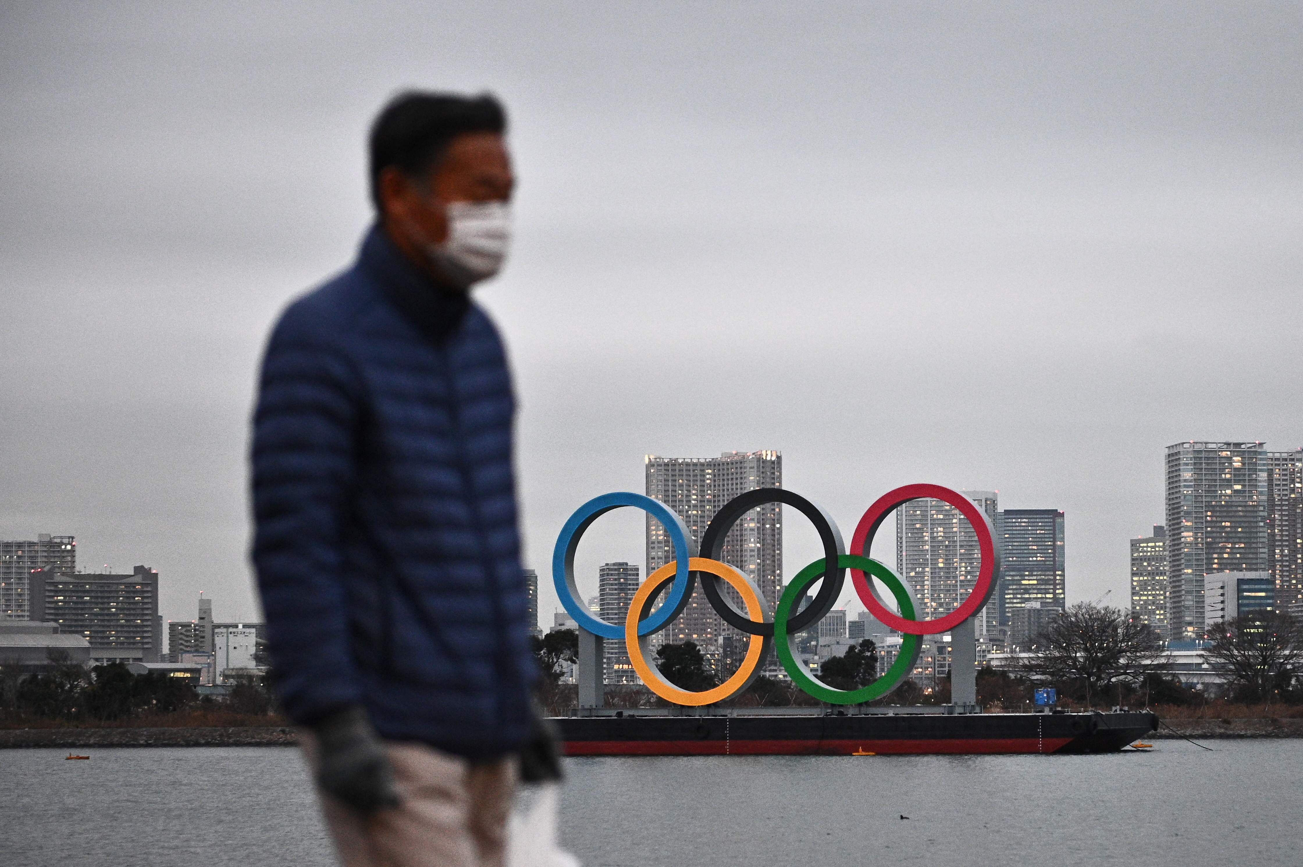 A man walks past the Olympic rings on display at the Odaiba waterfront in Tokyo. Credit: AFP Photo