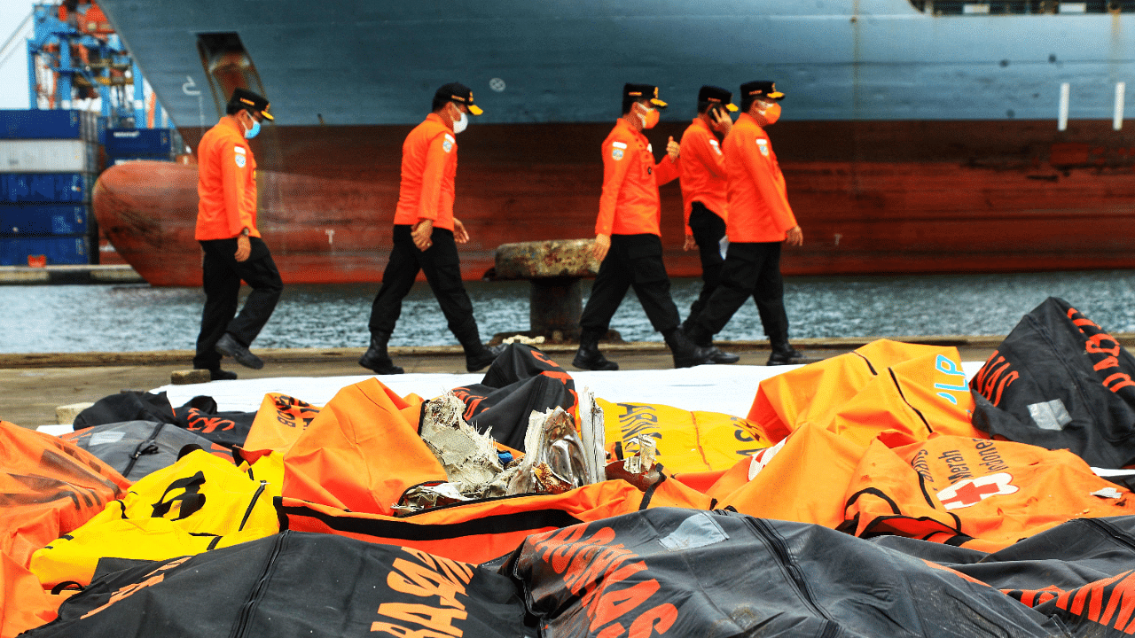 Rescue officials walk past debris collected during the search operation for Sriwijaya Air flight SJ182 at the port in Jakarta. Credit: AFP Photo