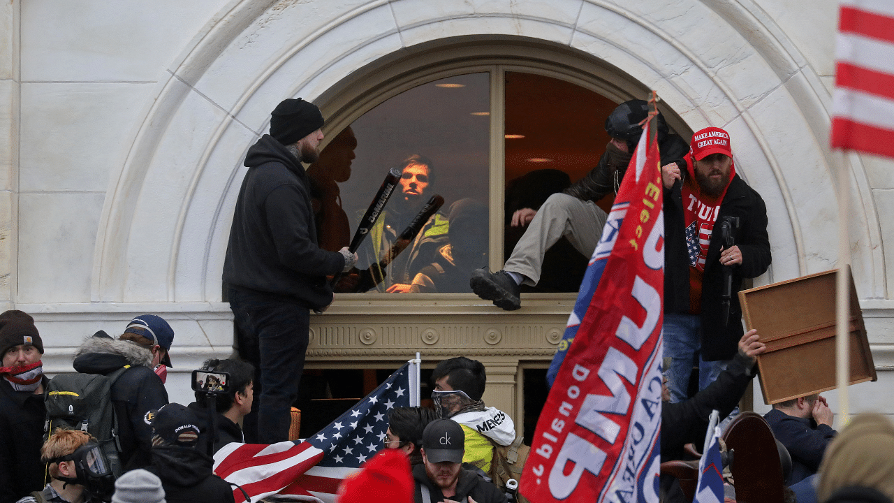 A mob of supporters of US President Donald Trump climb through a window they broke as they storm the US Capitol Building in Washington, US. Credit: Reuters File Photo