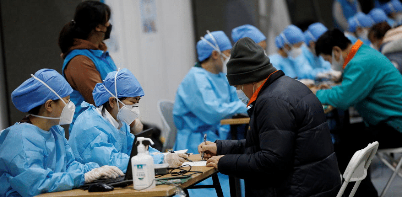 People fill forms before receiving a dose of a coronavirus disease (COVID-19) vaccine at a vaccination site. Credit: Reuters Photo