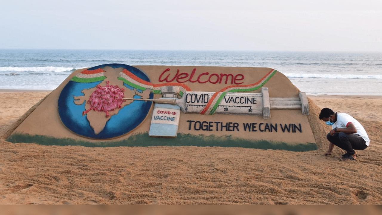 Sand artist Sudarshan Pattnaik creates a sand sclupture on the eve of the commencement of Covid-19 vaccination drive, at Puri beach, Friday, Jan. 15, 2021. Credit: PTI Photo