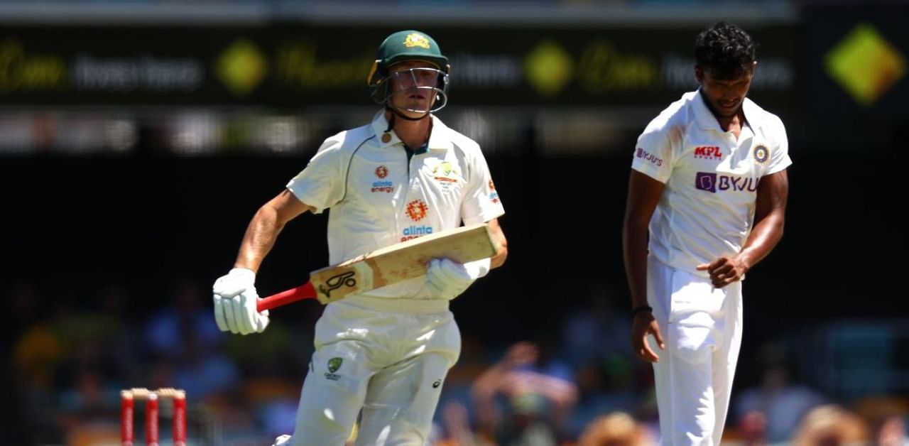 Australia's batsman Marnus Labuschagne runs between the wickets as India's paceman Thangarasu Natarajan (R) reacts after bowling on day one of the fourth cricket Test match between Australia and India at the Gabba in Brisbane on January 15, 2021. Credit: AFP Photo