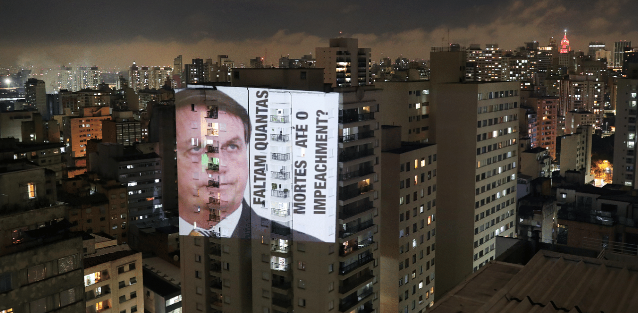An image of Brazil's President Jair Bolsonaro with the phrase "How many deaths until impeachment" is projected on a building during a protest. Credit: Reuters Photo