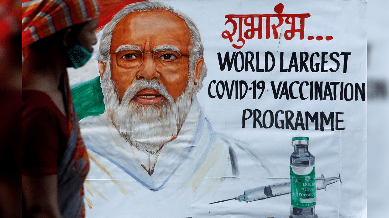 A woman walks past a painting of Indian Prime Minister Narendra Modi a day before the inauguration of the COVID-19 vaccination drive on a street in Mumbai, India, January 15, 2021. Credit: Reuters Photo