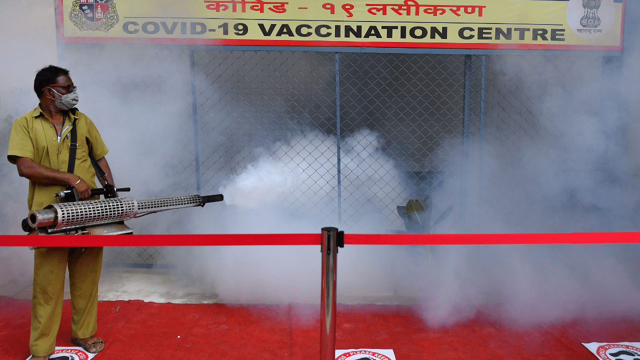 A civic authority worker fumigates a Covid-19 coronavirus vaccination centre as a preventive measure against diseases-carrying mosquitoes in Mumbai. Credit: AFP Photo.