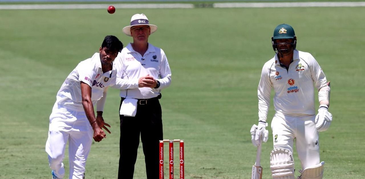 India's Washington Sundar (L) bowls as Australia's batsman Nathan Lyon (R) looks on during the day two of the fourth cricket Test match between Australia and India at The Gabba in Brisbane on January 16, 2021. Credit: AFP Photo
