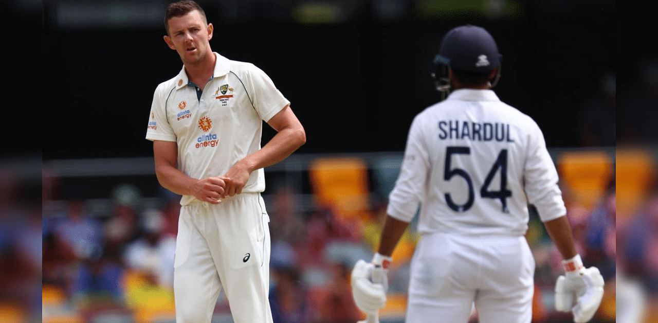 Australia's Josh Hazlewood (L) shares at India's batsman Shardul Thakur (R) on day three of the fourth cricket Test match between Australia and India at the Gabba. Credit: AFP Photo