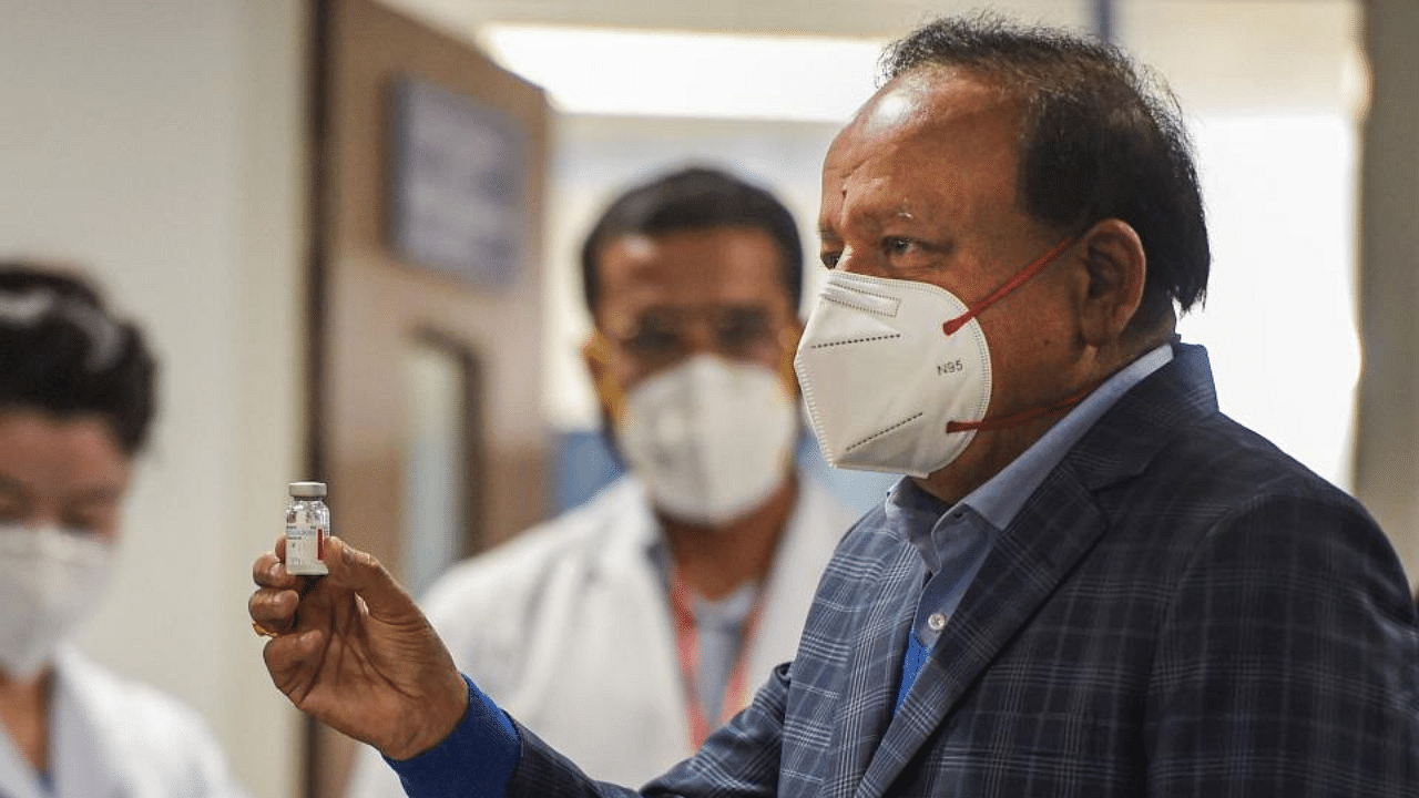 Union Health Minister Harsh Vardhan holds a vial of COVID-19 vaccine during the vaccination drive, at AIIMS in New Delhi, Saturday, Jan. 16, 2021. Credit: PTI Photo