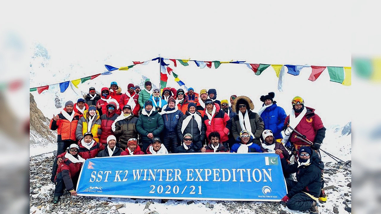 This handout photo taken on January 16, 2021 and released by Seven Summit Treks, shows mountaineers and Sherpas posing for pictures after reaching the summit of Mt K2, which is the second highest mountain in the world, at the Base Camp of the winter expedition in the Gilgit-Baltistan region of northern Pakistan. Credit: AFP