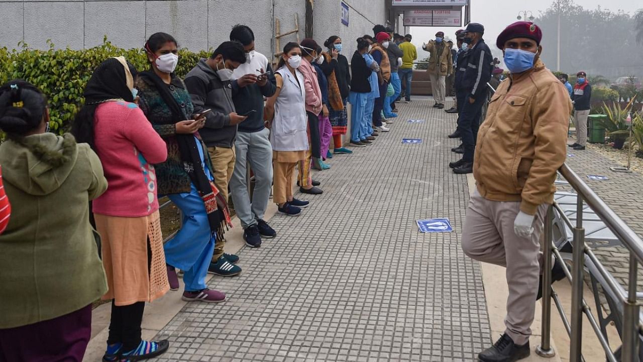 Health workers stand in a queue as they wait for their turn to get vaccinated, after the virtual launch of Covid-19 vaccination drive by Prime Minister Narendra Modi, at Rajiv Gandhi Super Speciality Hospital in New Delhi. Credit: PTI.