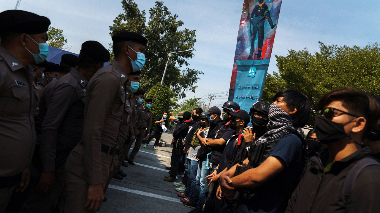 Volunteer guards of the anti-government protest movement stand guard in front of police officers at the Khlong Luang police station in Pathum Thani province, Thailand. Credit: Reuters Photo