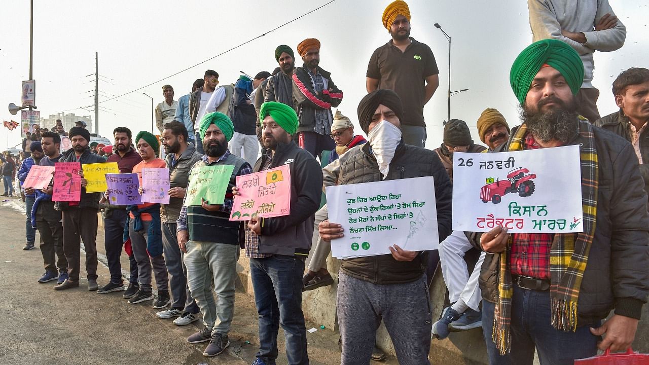 Farmers display placards during their ongoing protest against new farm law, at Ghazipur border in New Delhi, Tuesday, January 19, 2021. Credit: PTI Photo
