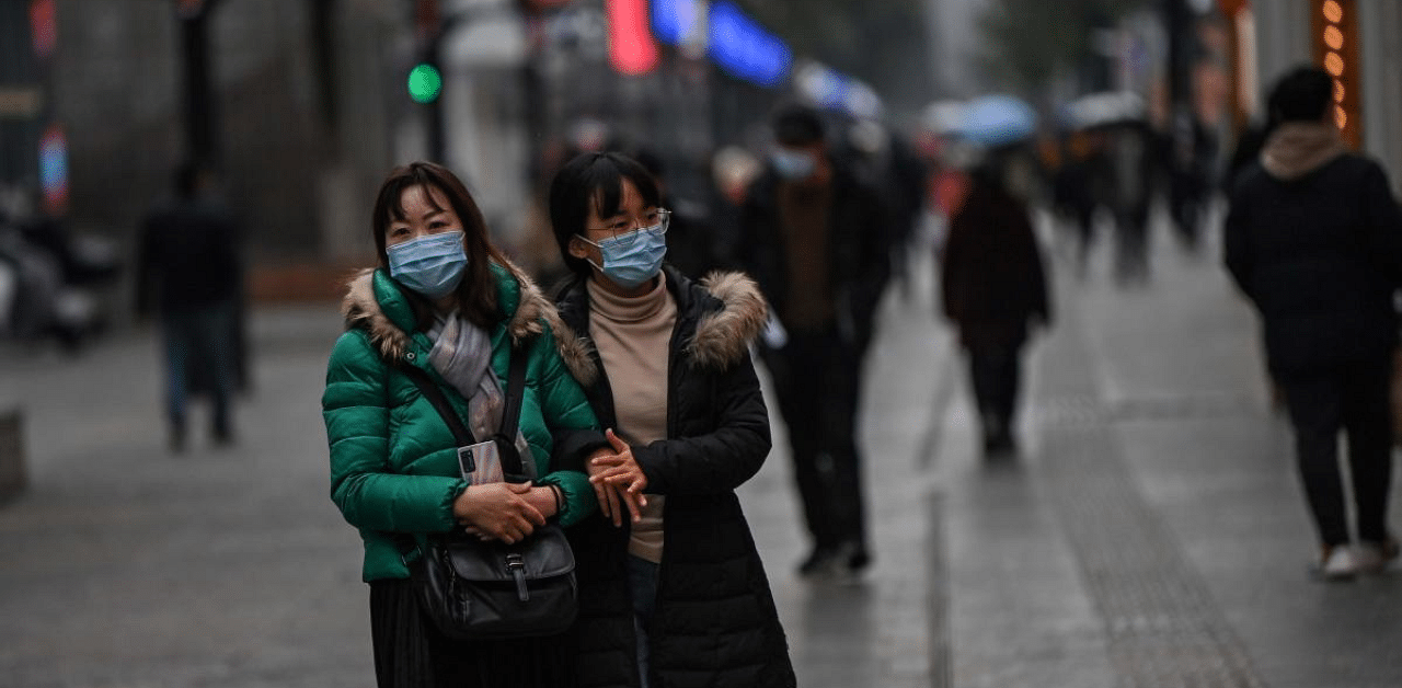 People wearing face masks as a preventive measure against the Covid-19 coronavirus walk on a street in Wuhan. Credit: AFP Photo