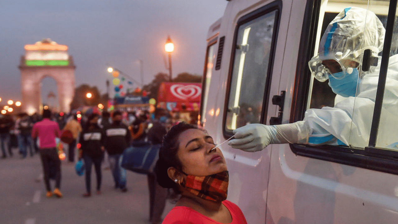  A health worker collects a sample from a woman for COVID-19 testing from a mobile van, organised by NDMC, at Rajpath in New Delhi, Sunday, Nov. 22, 2020. Credit: PTI Photo