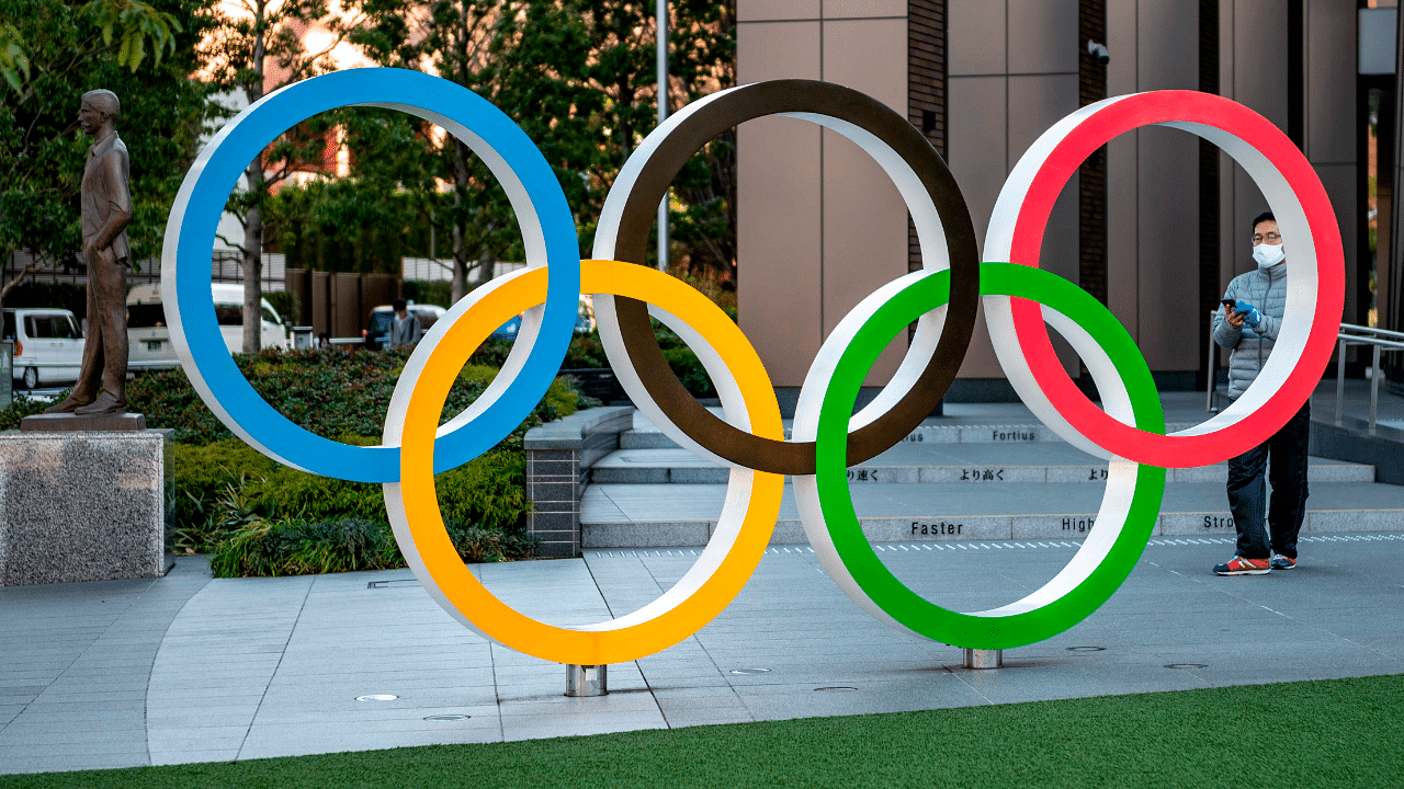 This picture taken on January 20, 2021 shows a visitor taking photos of the Olympic rings outside the Olympic Museum in Tokyo. Credit:  AFP File Photo