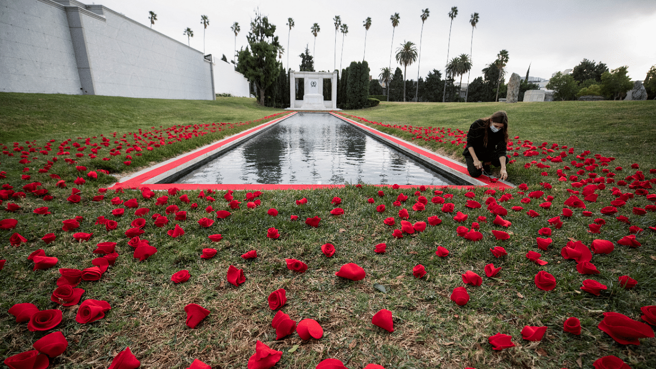 A person lights a candle by a tribute to the victims of the Covid-19 pandemic by the Reflecting Pool at the Hollywood Forever Cemetery during the outbreak of Covid-19, in Los Angeles, California, US. Credit: Reuters File Photo
