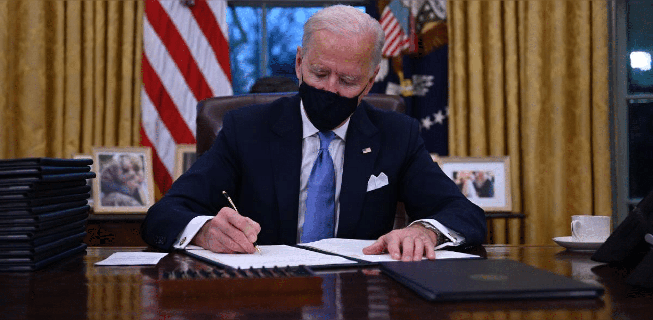 US President Joe Biden sits in the Oval Office as he signs a series of orders at the White House in Washington, DC, after being sworn in at the US Capitol on January 20, 2021. Credit: AFP. 