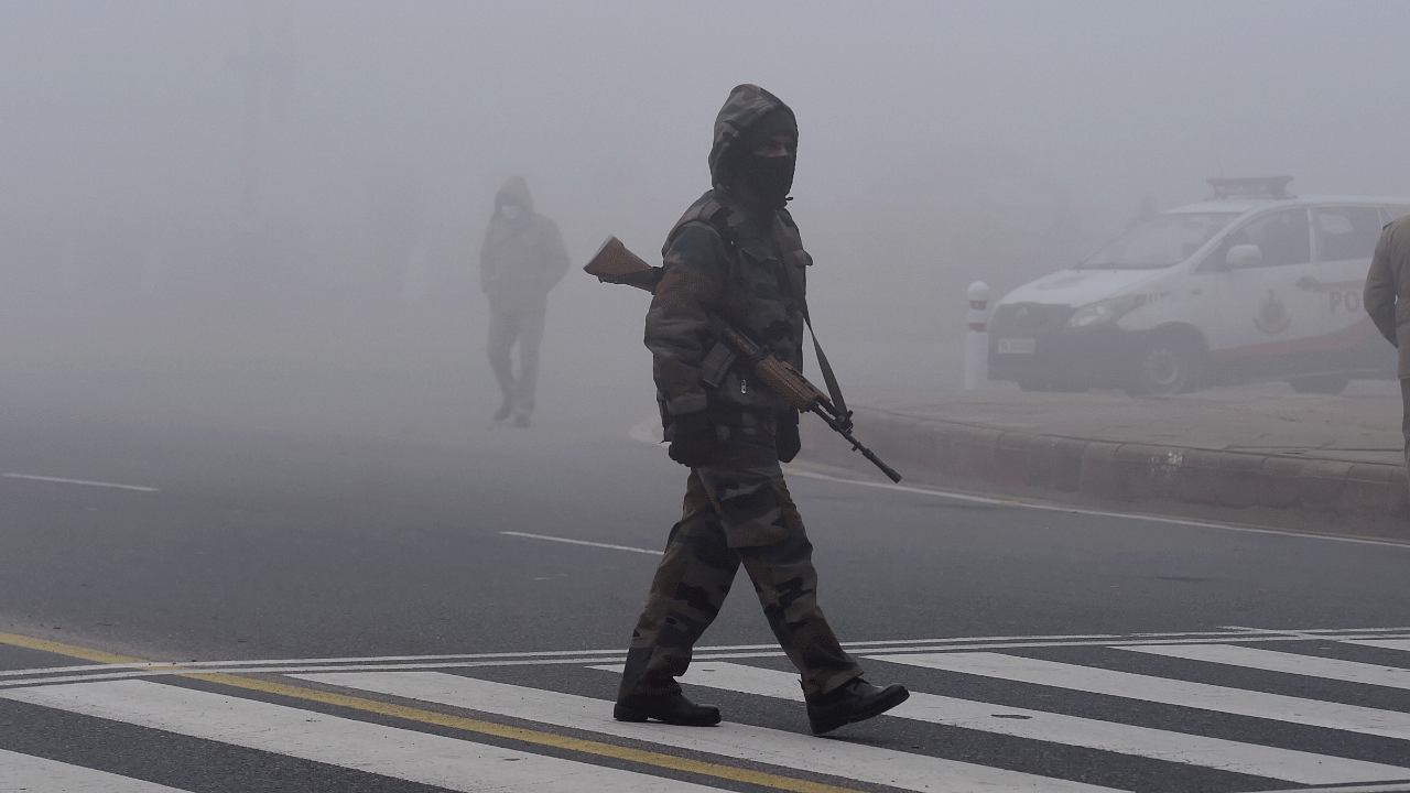 A security personnel walks across a road during the rehearsals for Republic Day Parade amid dense fog at Rajpath, in New Delhi. Credit: PTI File Photo