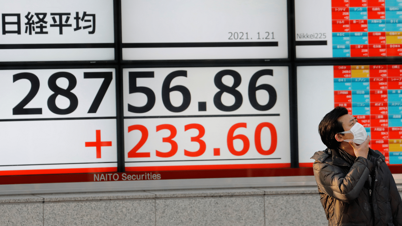 A man wearing a protective mask, amid the Covid-19 outbreak, stands in front of an electric board showing Nikkei index outside a brokerage in Tokyo, Japan. Credit: Reuters Photo