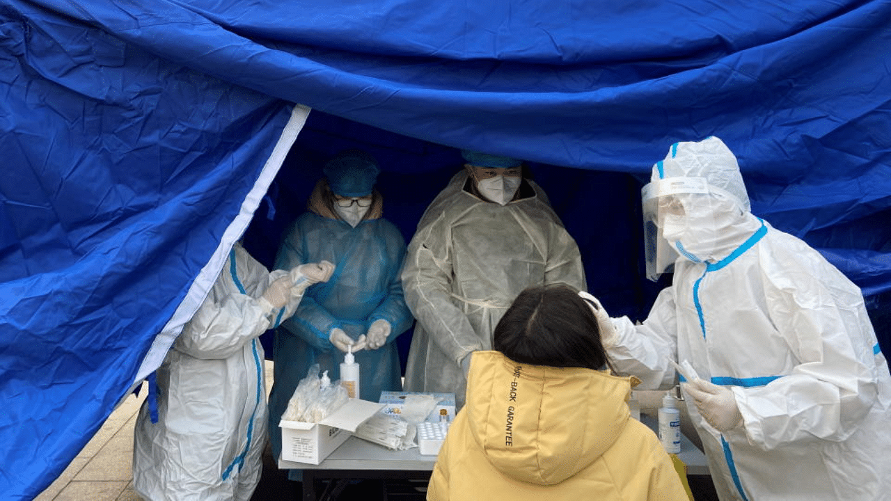 A medical worker in a protective suit collects a swab from a woman for nucleic acid testing at a makeshift testing site following the coronavirus disease (COVID-19) outbreak in Beijing, China January 22, 2021.  Credit: Reuters Photo