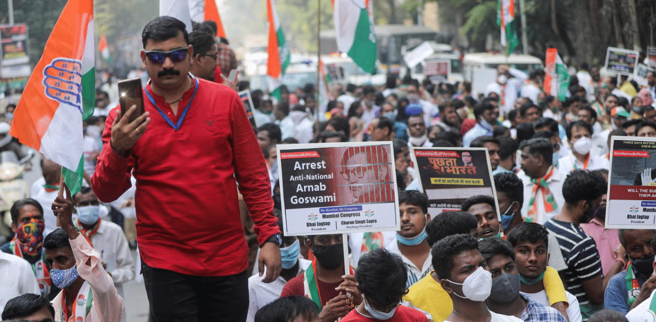 A man holds a phone as supporters of India's main opposition Congress party hold placards with pictures of Arnab Goswami, one of India's top TV news anchors, during a protest in Mumbai. Credit: Reuters Photo