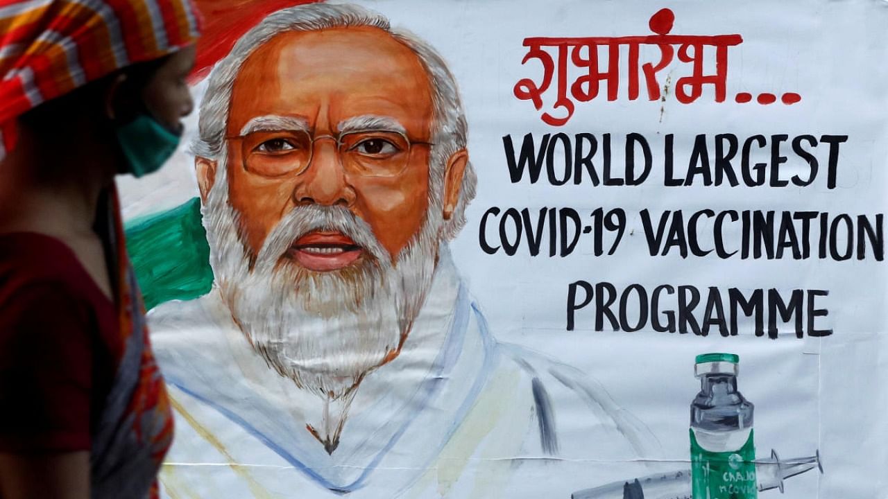 A woman walks past a painting of Indian Prime Minister Narendra Modi a day before the inauguration of the Covid-19 vaccination drive on a street in Mumbai, India, January 15, 2021. Credit: Reuters Photo