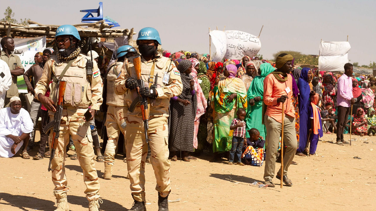 Members of the United Nations and African Union peacekeeping mission (UNAMID) look on as Sudanese internally displaced people stage a sit in to protest against the end of their mandate, in Kalma camp in Nyala, the capital of South Darfur. Credit: AFP Photo