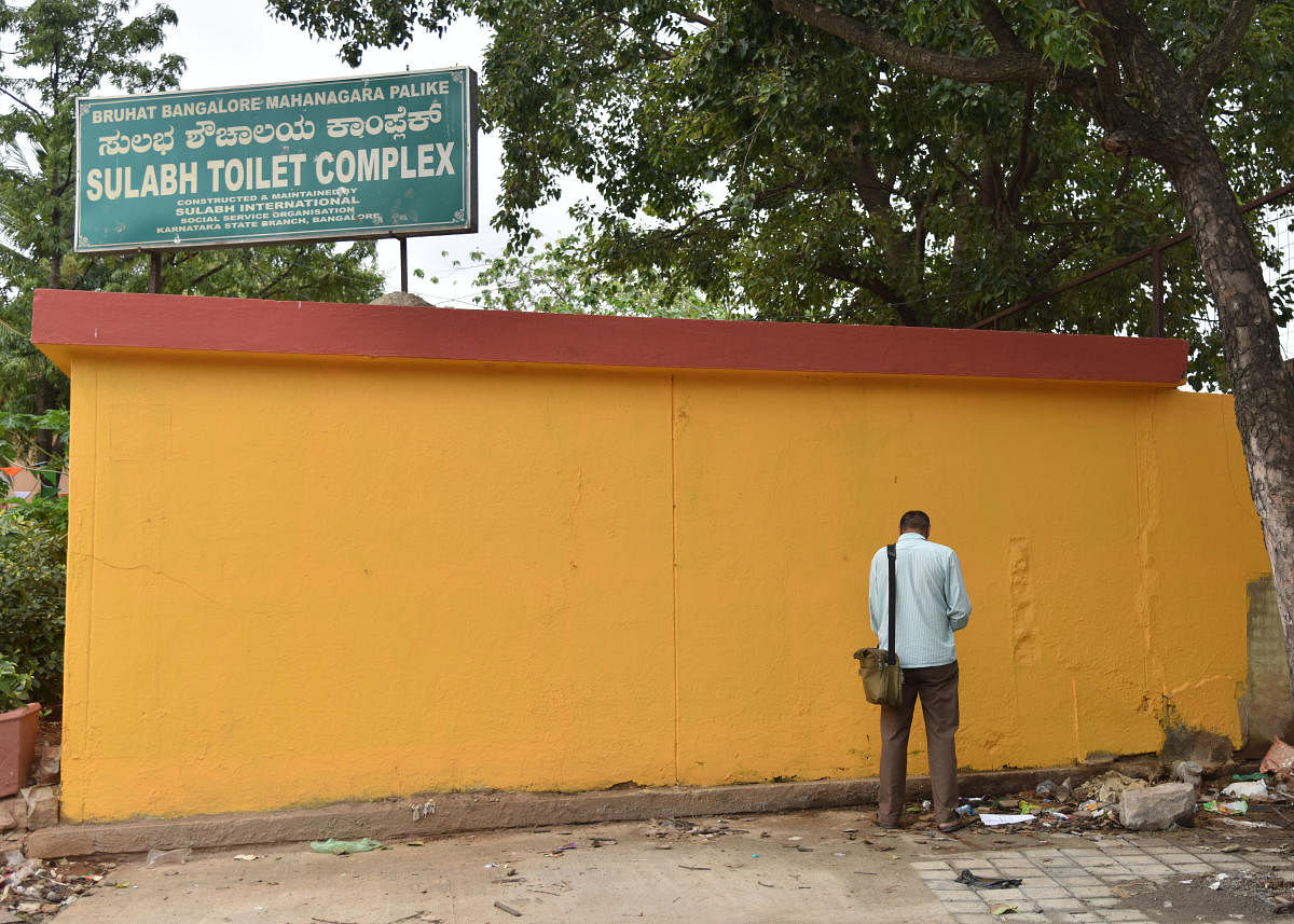 Man urinates on the wall of a public toilet at Majestic. Constructing more toilets is no solution if people aren’t aware of the ills of urinating in public, say civic activists. DH Photo by Janardhan BK