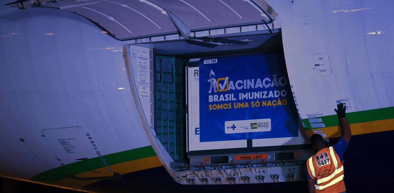 Containers carrying doses of the Oxford/AstraZeneca vaccine with a banner reading “Vaccination. Brazil immunized. We are an only nation” are unloaded from a cargo plane that arrived from India at the Galeao airport, in Rio de Janeiro, Brazil. Credit: AFP. 