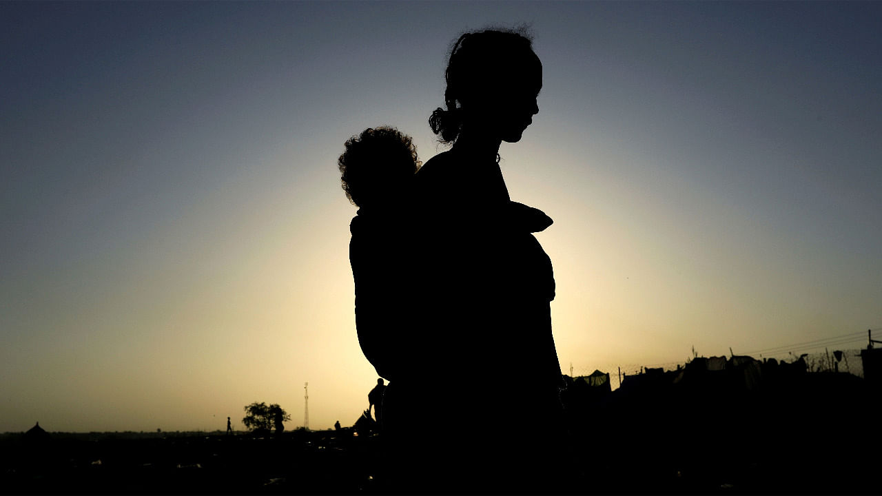 An Ethiopian woman who fled the ongoing fighting in Tigray region, carries her child near the Setit river on the Sudan-Ethiopia border in Hamdayet village in eastern Kassala state, Sudan. Credit: Reuters Photo