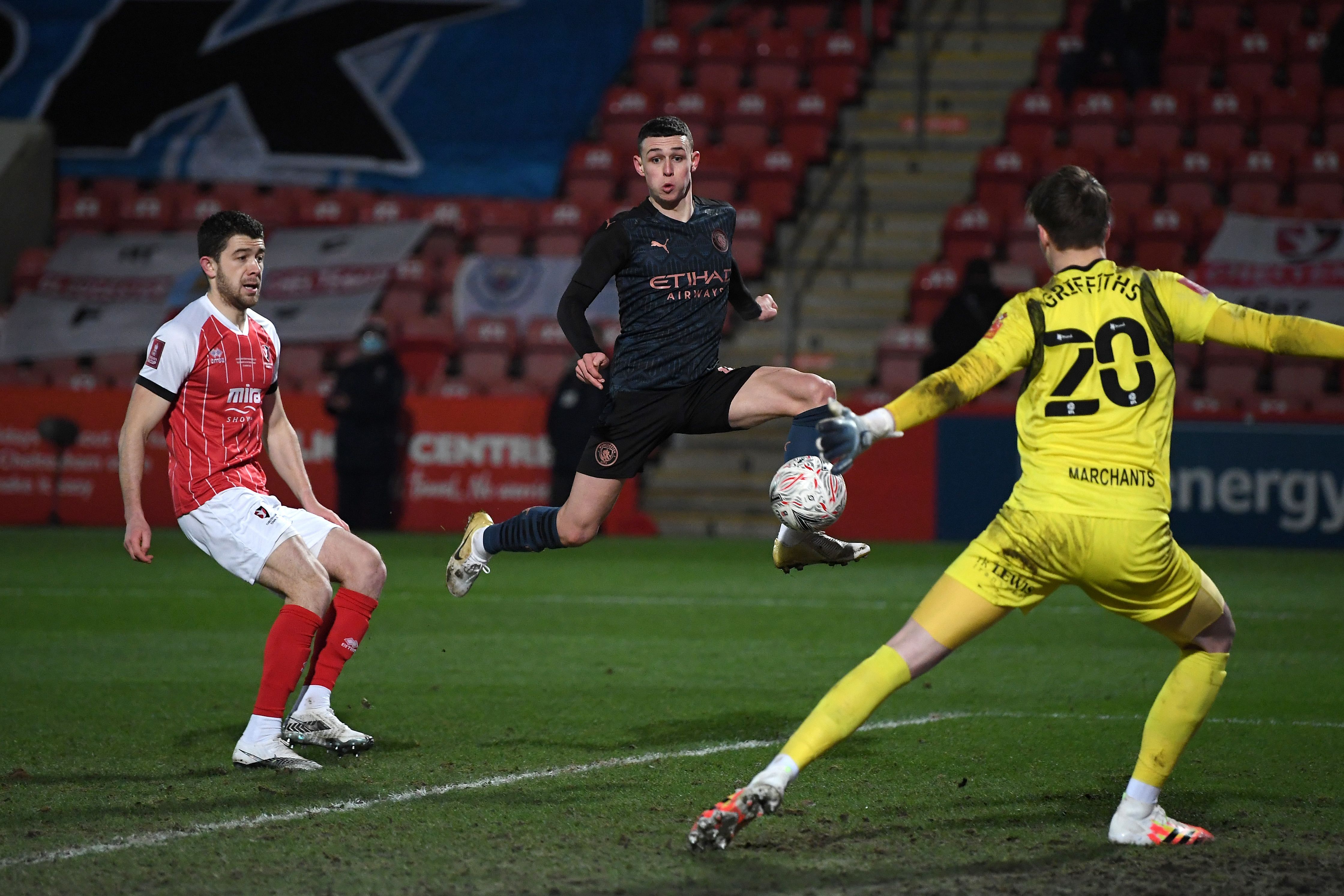 Manchester City's English midfielder Phil Foden (C) shoots to score their first goal during the English FA Cup fourth round football match between Cheltenham Town and Manchester City at The Jonny-Rocks Stadium in Cheltenham, central England. Credit: AFP Photo