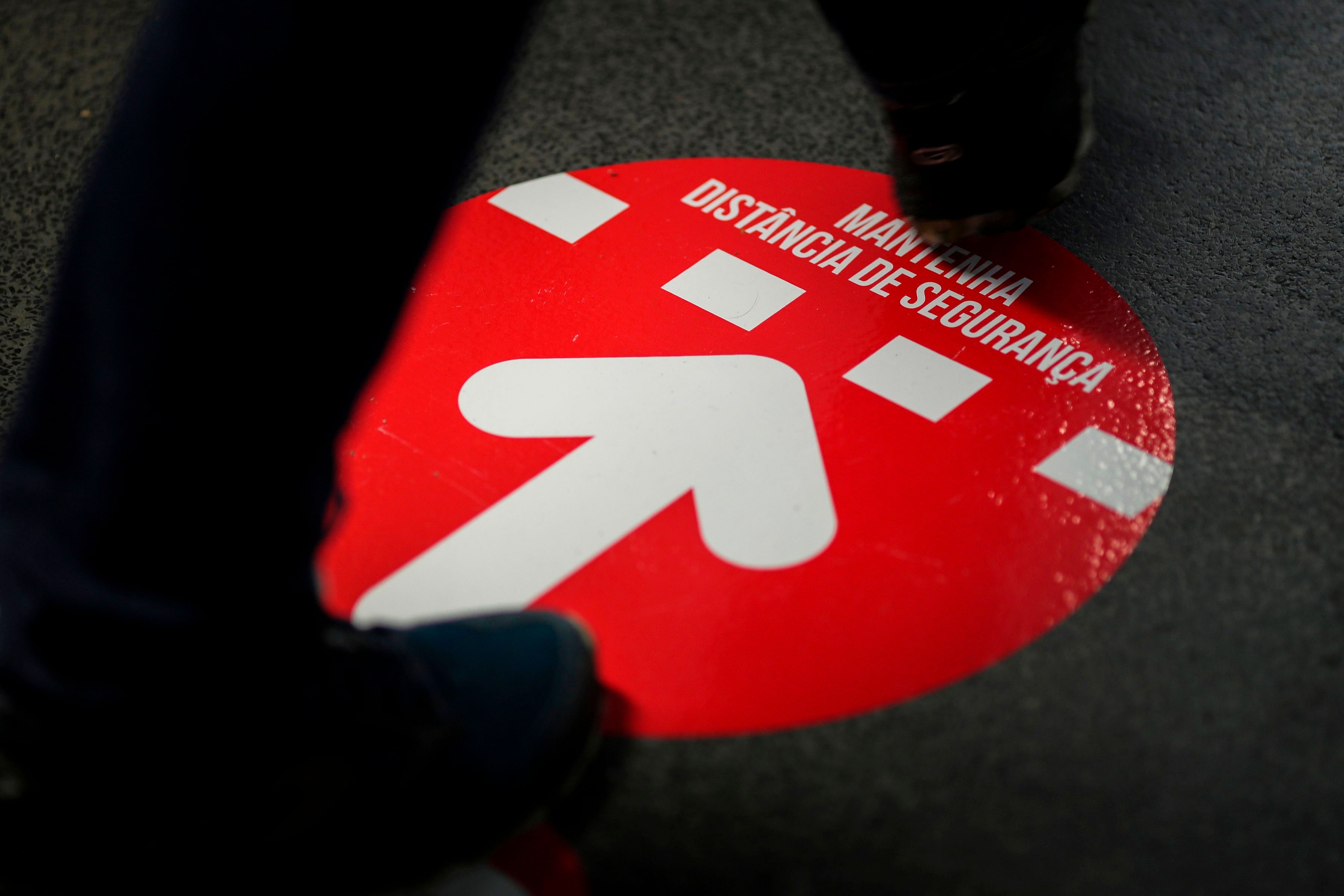 A voter walks over a social distancing sign during the Portuguese presidential election at a polling station in Parque das Nacoes in Lisbon on January 24, 2021. - Portugal is voting despite the country's pandemic lockdown. Credit: AFP Photo